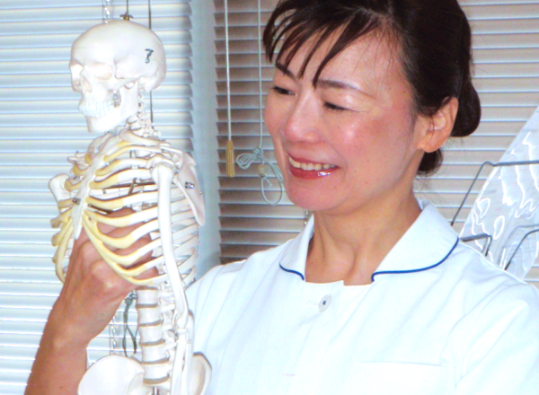 タニカワ久美子が骨格モデルを持ちながら笑顔で説明している